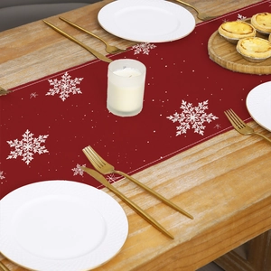 Christmas table runner with white snowflakes on red fabric over a rustic wooden table