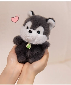 Close-up of a small grey husky plush toy keychain held in hands with sprout detail