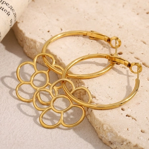 Détail macro de créoles en acier inoxydable doré 18 carats avec breloques fleurs