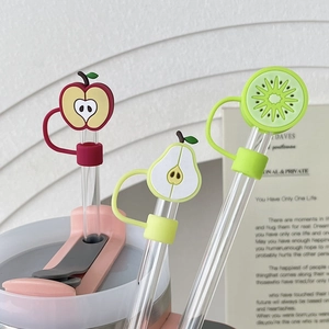Close-up of three reusable straws with fruit-shaped silicone dust caps: apple, pear, kiwi