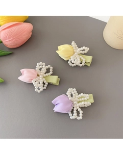 Detailed view of yellow, pink, and purple tulip hair clips with pearls and fabric leaves