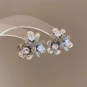 Macro shot of silver flower earrings with sparkling zircons and polished metal finish