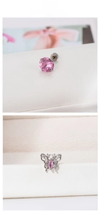 Détail macro de boucle d'oreille papillon argentée avec zircon rose et clou classique