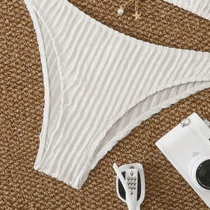 Detail of white bikini bottoms with textured fabric and starfish chain on straw mat