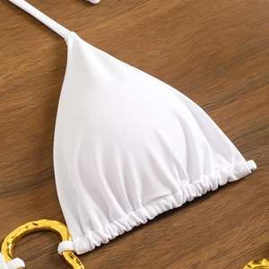Close-up of white bikini top with elegant gold metal ring detail and pleated fabric texture