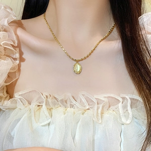 Vintage gold beaded necklace with oval cat eye stone pendant worn by model on lace collar