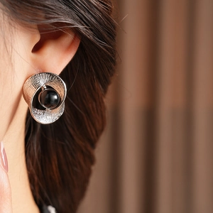 Detail view of silver twisted earring with black gemstone inlay worn by a model