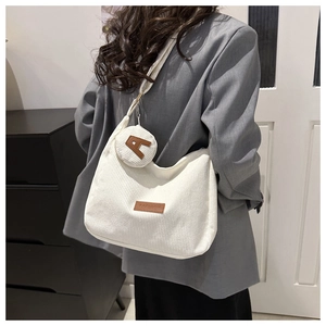 Detail of off-white corduroy tote with brown FASHION patch and round mini coin purse