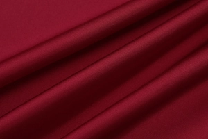 Detailed macro view of the glossy wine red satin fabric with elegant drape and silky texture