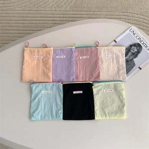 Flat lay of colorful nylon makeup bags in seven macaron shades with ring zippers