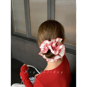 Detailed back view of model wearing a red and white checkered lace scrunchie hair tie