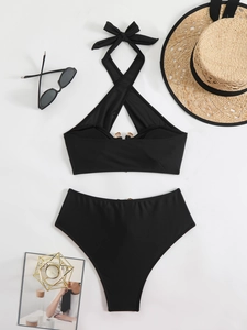 Flat lay of black halter bikini with gold clasp, high-waisted bottom and chic accessories