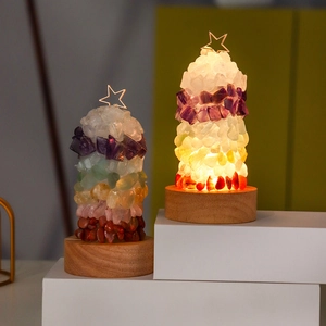 Detail of crystal tree night lights with natural gems on round wooden base in warm glow