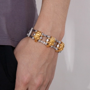 Close-up of men's rock style skull and bike chain bracelet in gold and silver finish