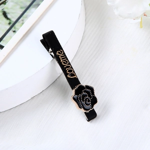 Detail einer schwarz-goldenen Rosen-Haarklammer mit love me Schriftzug und Emaille-Finish