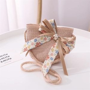 Close-up of pink straw crossbody bag with floral bow and ribbon for summer beach outings