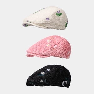 Detail of corduroy berets featuring floral embroidery in beige, pink, and black colors