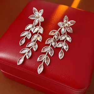 Detail of silver leaf tassel earrings with marquise zircon on a red leather box