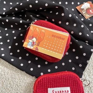 Detail of red plush and corduroy mini pouches with silver zippers and hanging rings