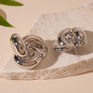 Detail shot of silver knot stud earrings with liquid metal finish on a stone base