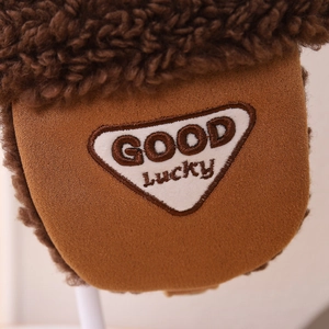 Detail of brown fleece winter hat featuring Lucky Bear embroidery and plush texture