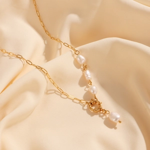 Detailed macro view of 18K gold paperclip chain and natural freshwater pearl pendant