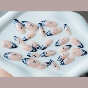 Almond French press-on nails with blue hibiscus flowers and black accents on white ceramic