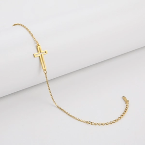 Detailed view of a minimalist hollow cross pendant on a golden bracelet chain
