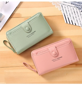Detail of pink and green long wallets with wrist straps and pebbled leather texture