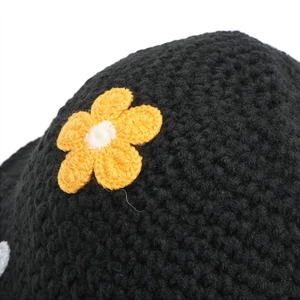 Detailed macro view of black hand-knit crochet texture with decorative yellow floral accents