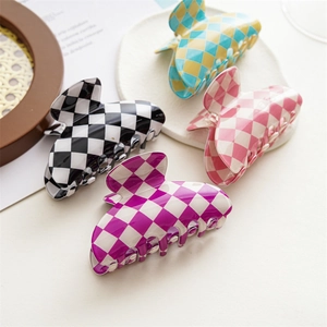 Checkboard hair claws in various colors like black, blue, and pink displayed on stone