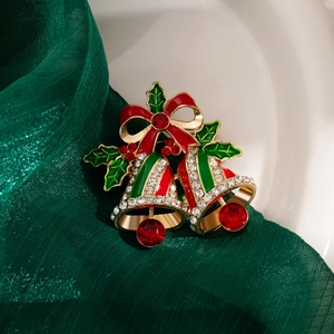 Detail of Christmas bell brooch with red enamel bow and crystal inlay on green silk