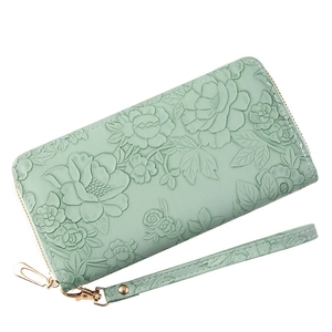 Light green long wallet with floral embossing and detachable wristlet strap in studio view