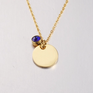 Close-up of golden stainless steel round pendant with a blue sapphire birthstone charm