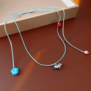Close-up of adjustable cord necklace with dachshund dog and blue flower pendants