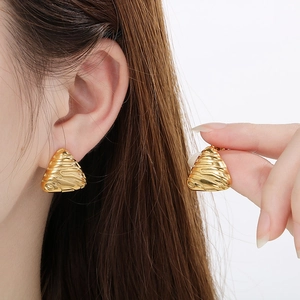 Close-up of golden triangle stud earrings with vintage embossed brushed metal texture