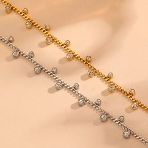 Detailed view of gold and silver anklets with sparkling zircon charms on a soft beige background