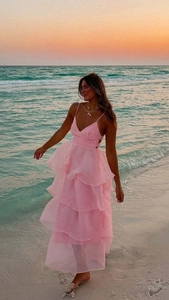 Detail view of pink layered ruffle cake dress with thin straps against sunset beach background