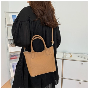 Détail du sac seau en cuir grainé caramel avec bord ondulé et clous métalliques