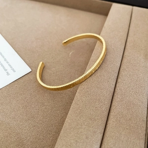 Detailed macro view of 18k gold plated ribbed texture and matte finish on open cuff bracelet