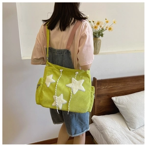 Borsa a tracolla in velluto a coste verde con stelle bianche indossata da una modella