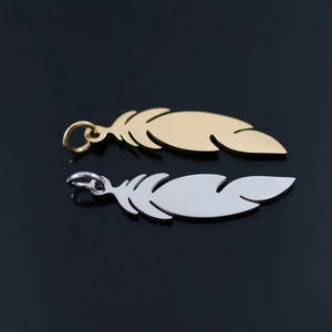 Detailed macro view of 18K gold and silver steel feather pendants on black mirror surface