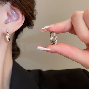 Close-up of Mobius silver earrings with pavé zircons worn on ear for minimalist detail