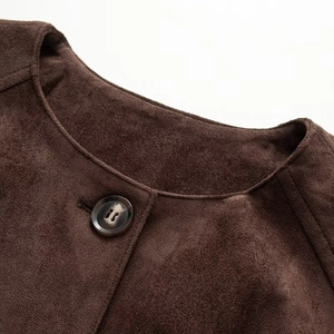 Detail shot of a dark brown faux leather jacket featuring a crew neck and fine stitching