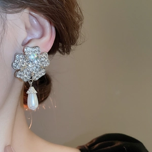 Detail view of silver flower earrings with rhinestones and teardrop pearl on model