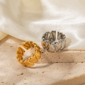 18K gold and silver stainless steel heart open rings displayed on a beige stone