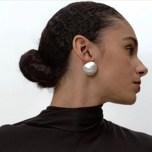 Gros plan de grandes boucles d'oreilles argentées brossées portées par un mannequin