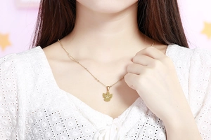 Dettaglio della collana dorata con ciondolo lettera W su modella con abito in pizzo