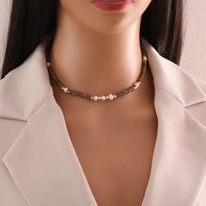 Close-up of handmade necklace with dark stone beads, white pearls and gold accents