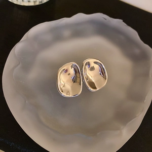 Detailed view of silver irregular liquid metal earrings on frosted tray background